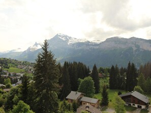 Un paysage montagneux avec un village et plusieurs maisons en bois, le tout entouré de forêts denses.