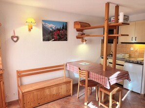 A cozy kitchen with wooden furniture, a bench, and a dining table with a checkered tablecloth.