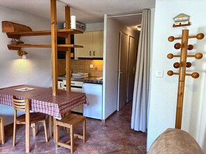 A compact kitchen with a dining area, wooden furniture, and a curtain rod.