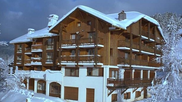 Un chalet en bois à plusieurs étages, doté de balcons et entouré de neige.
