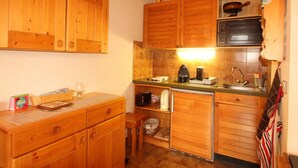 A compact kitchen with wooden cabinets, a microwave, a coffee maker, and a sink. - Studio for 4 at the foot of the slopes, balcony, ski locker, TV (Les Carroz d'Arâches)