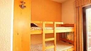 A bunk bed room with a wooden door and a window with plaid curtains. - Studio for 4 at the foot of the slopes, balcony, ski locker, TV (Les Carroz d'Arâches)