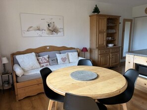 A cozy room with a wooden sofa, a round dining table, and a cabinet. - Charming 2-Bedroom Apt for 5 Near Pistes and Shops, Great Amenities (Les Carroz d'Arâches)