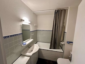A bathroom with a sink, mirror, bathtub, and toilet.