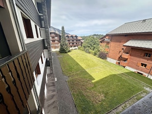 A courtyard with a lawn, a stone wall, and buildings with balconies.