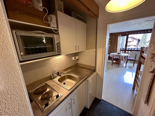 A compact kitchen with a microwave, sink, and stove.