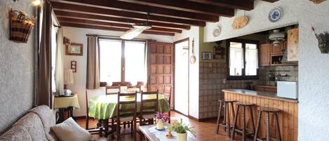 A cozy living room with a sofa, a wooden coffee table, and a dining area with a table and chairs.
