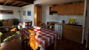 Eine gemütliche Küche mit Holzausbau, einem Esstisch mit karierter Tischdecke und einem Sofa im Wohnbereich.