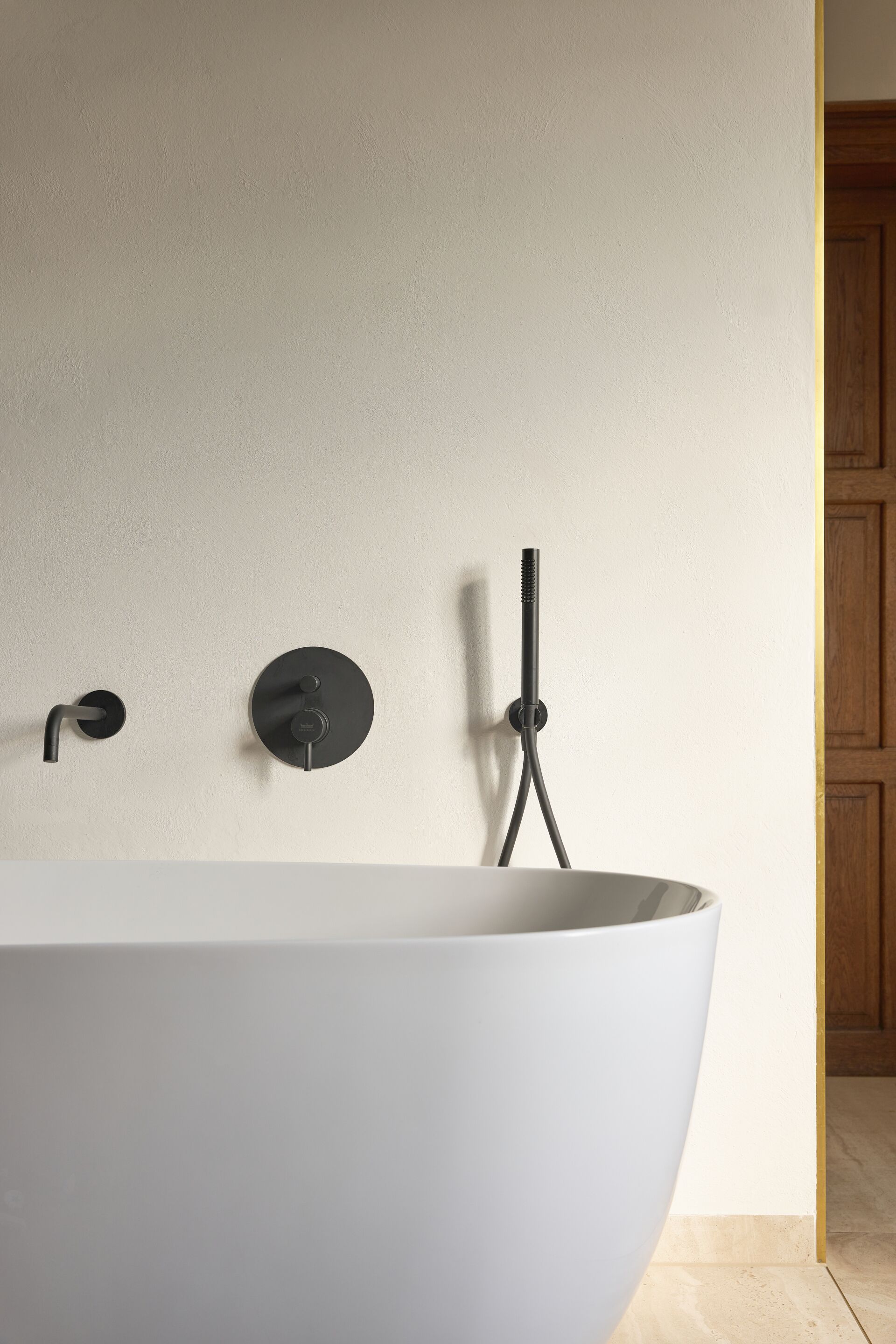 Une salle de bain moderne avec une baignoire sur pieds, un robinet mural et une douchette à main.