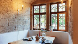 A cozy room with a wooden table set for tea, a vase with flowers, and a window with a view of greenery. - Urlaub im Wasserschloss Irmelshausen (Höchheim)