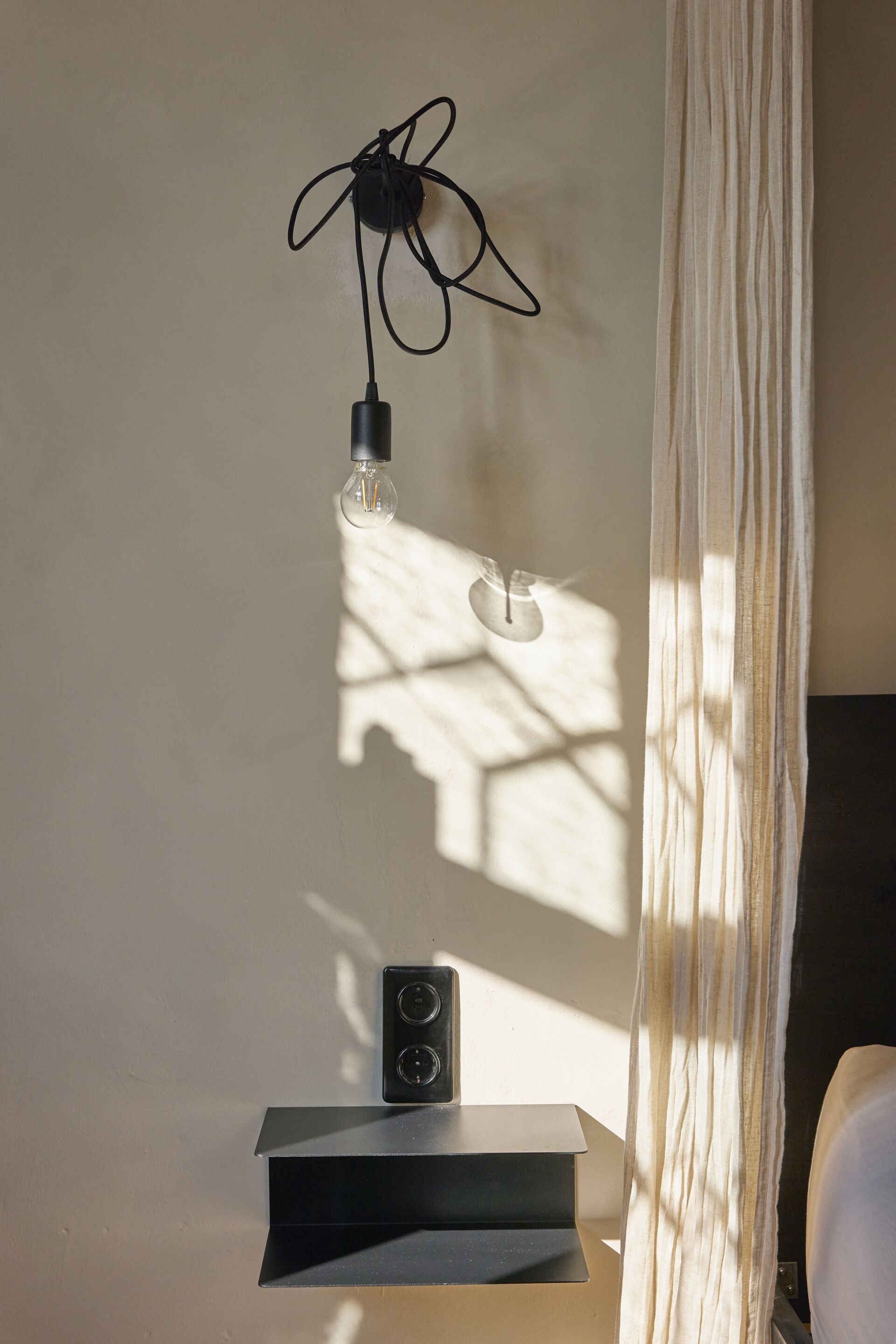 A room with a wall-mounted light fixture, a speaker, and a curtain.