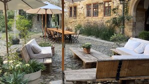 A courtyard with stone flooring, outdoor seating, and umbrellas. - Urlaub im Wasserschloss Irmelshausen (Höchheim)