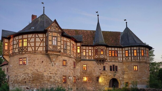 A historic building with multiple towers and a central courtyard. - Urlaub im Wasserschloss Irmelshausen (Höchheim)