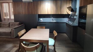 A modern kitchen with a dining area, featuring a built-in oven, a sink, and a coffee maker. -  A rare minimalist concept in a quiet location with skyline view (Yerevan)