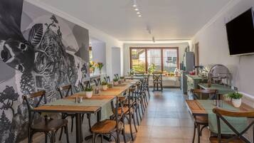 Un comedor con una larga mesa, sillas y un mural en la pared.