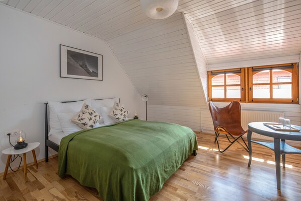 A bedroom with a bed, a chair, a table, and a window. - Ferrata Guesthouse (Csesznek)