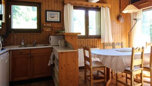 L’intérieur d’un chalet en bois comprend une cuisine, un coin repas et de grandes fenêtres.