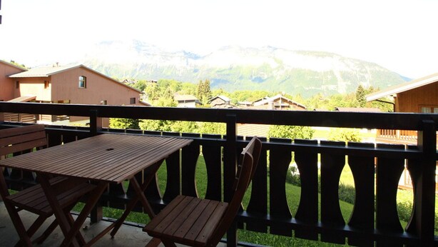 Un balcón con mobiliario de madera que ofrece vistas a un paisaje montañoso.