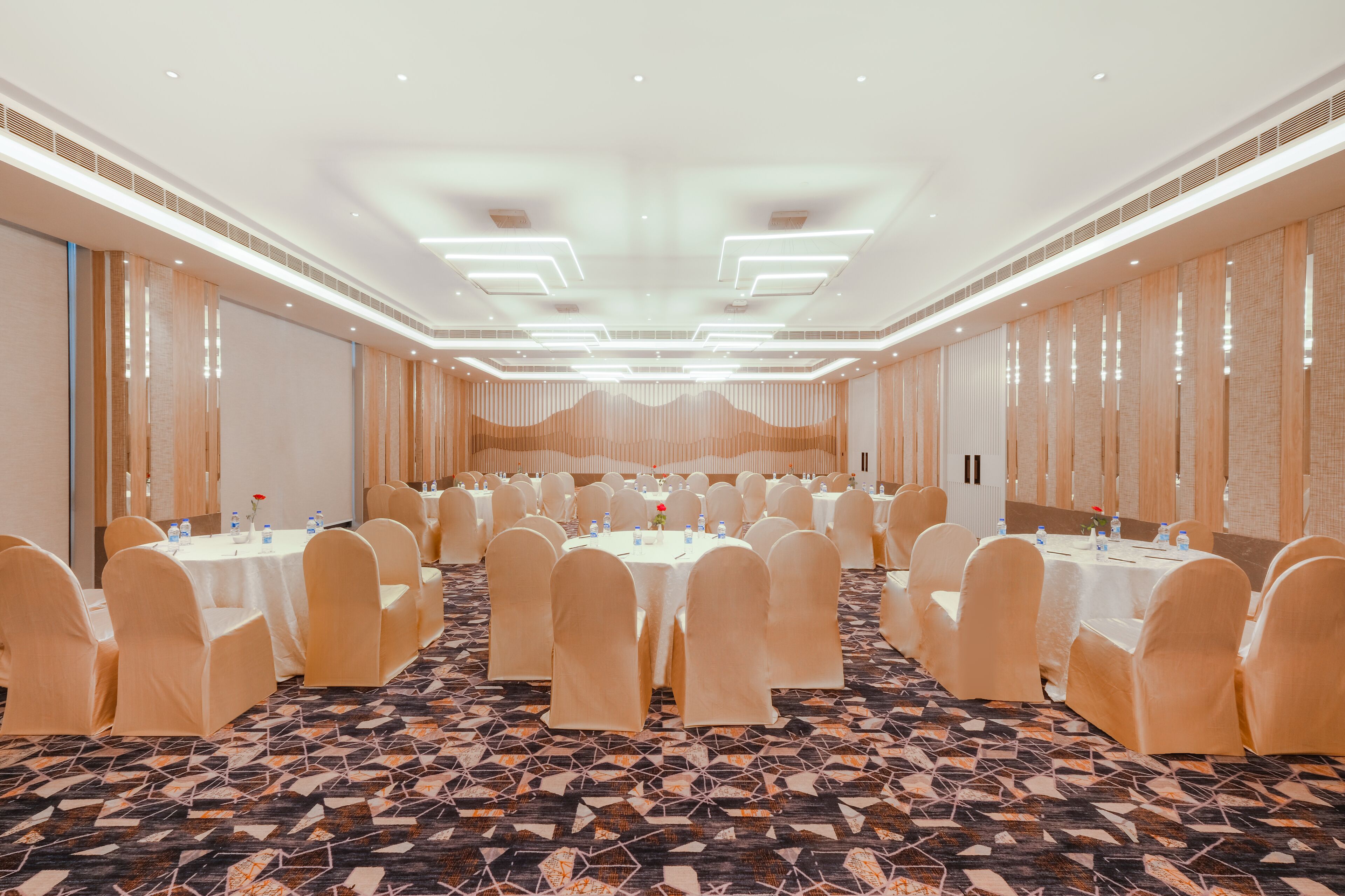 Une salle de conférence avec des tables rondes, des chaises et un tapis à motifs.