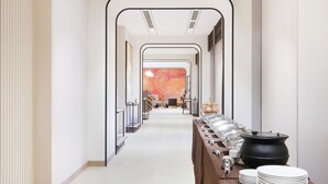 A corridor with a long table set up for a buffet, leading to a room with a decorative wall. - 7 Apple Hotel Nashik (Nashik)
