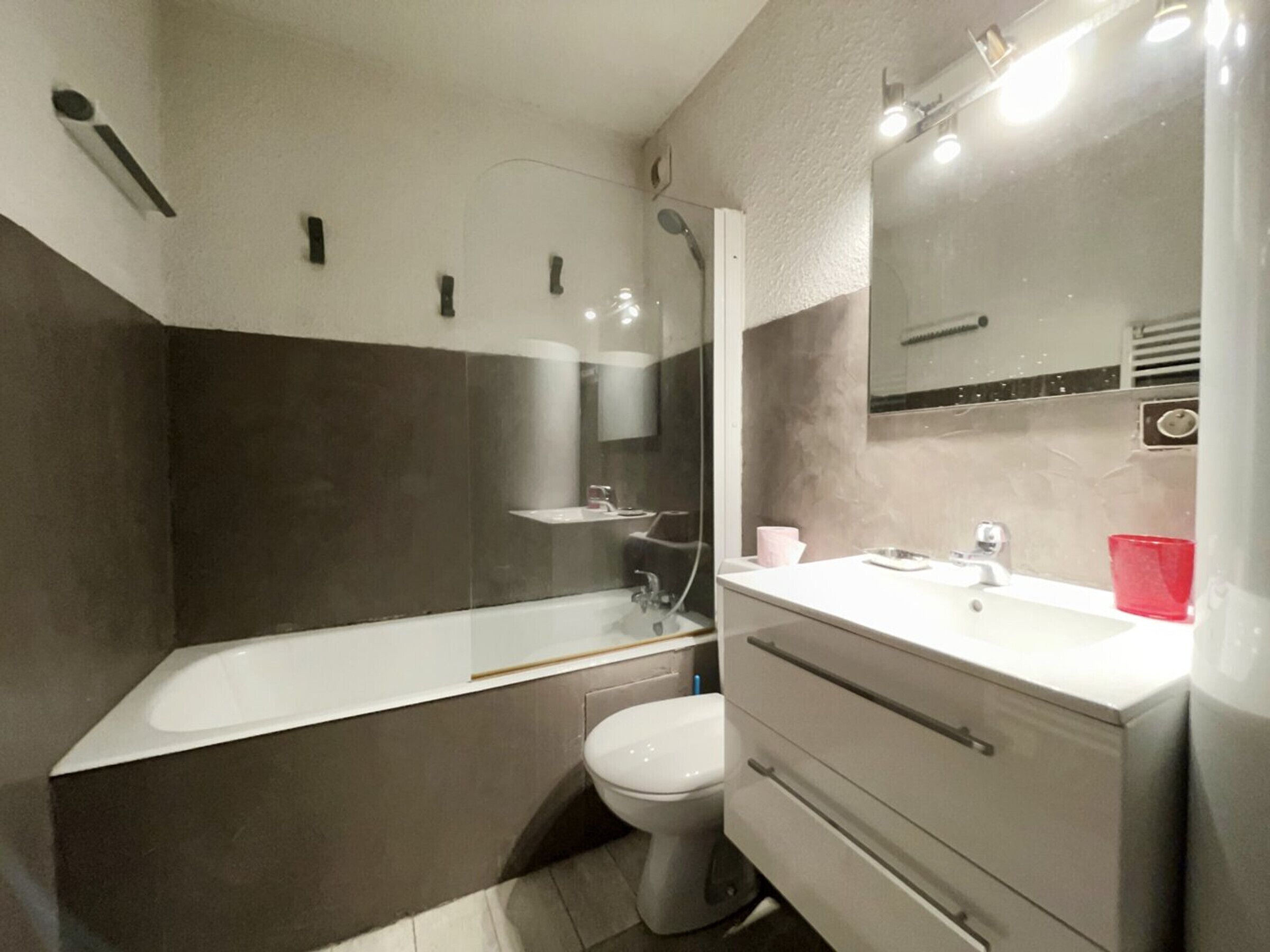 Une salle de bain moderne équipée d’une baignoire, de toilettes et d’un meuble-lavabo.