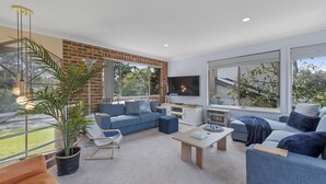 Una sala de estar moderna con un sofá azul, una mesa de centro y un televisor montado en la pared.