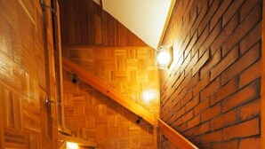 A wooden staircase with a brick wall on one side and a wooden door on the other.