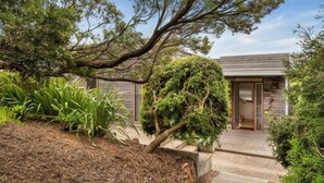 A modern house with a wooden deck, surrounded by lush greenery and a large tree. - Sorrento Sea Escape. (Sorrento)
