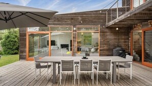 An outdoor deck with a dining table and chairs, a grill, and a large umbrella. - Sorrento Sea Escape. (Sorrento)