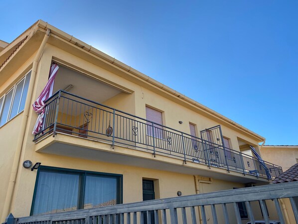 A two-story building with balconies, large windows, and a clear sky.