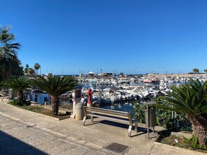 A marina with boats docked, a clear blue sky, and a bench in the foreground. - Limoneto ground floor (Trabia)