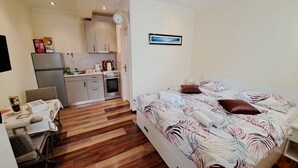 A compact hotel room with a bed, a small kitchenette, a dining area, and a view of the cityscape. - Studio Nina Apartment (Novigrad)