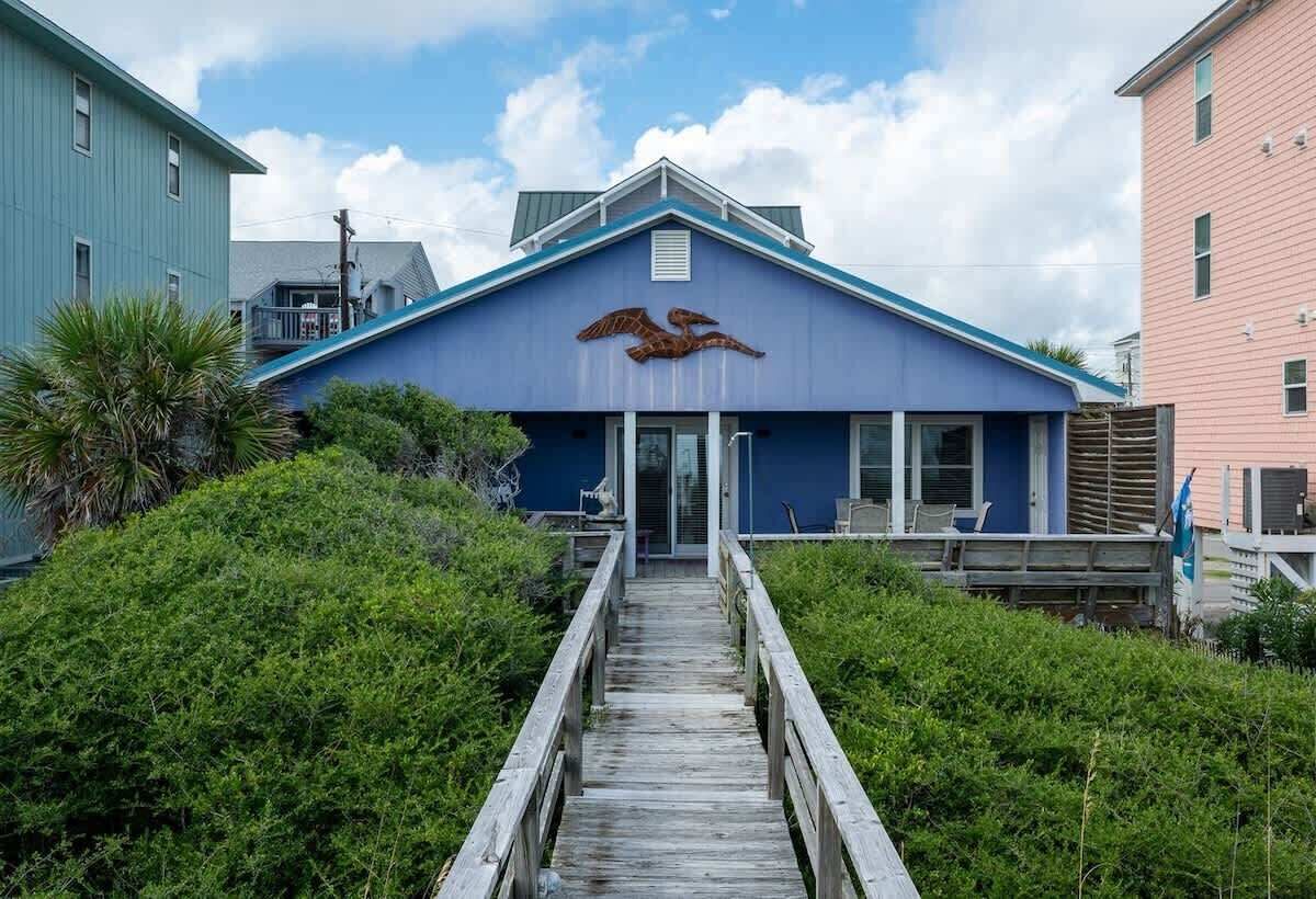 A building with a blue facade and a wooden staircase leading to the entrance.