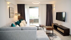 Ein modernes Wohnzimmer mit grauem Sofa, einem Flachbildfernseher und einem Balkon mit Blick.