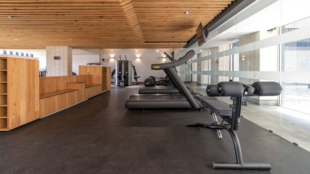 Ein Fitnessstudio mit Holzbänken, Laufbändern und Krafttrainingsgeräten.