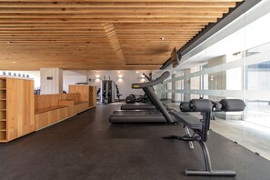 A gym with wooden benches, treadmills, and weight machines.