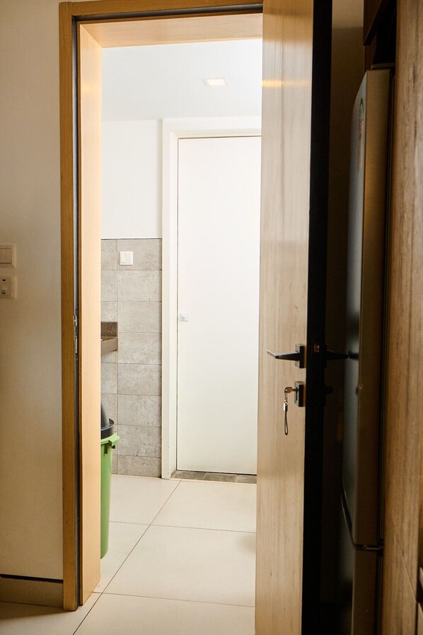 An open door leading to a room with a tiled floor and a white door in the background.