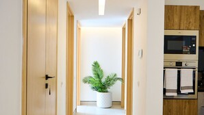 Ein Flur mit Holztüren, einem Blumentopf und einer Mikrowelle im Küchenbereich.