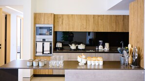 Eine moderne Küche mit Holzschränken, einem eingebauten Ofen, einer Kaffeemaschine und verschiedenen Küchenutensilien.
