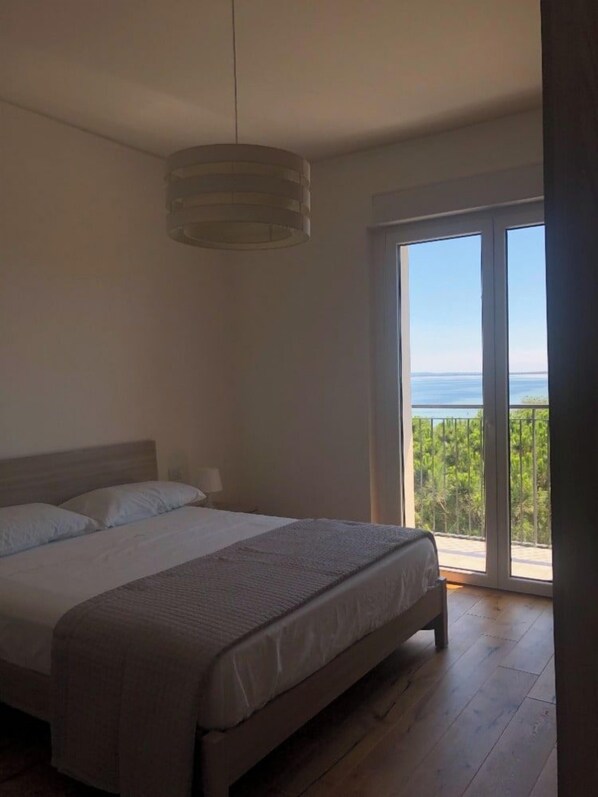 A bedroom with a large bed, a hanging light fixture, and a view of the outdoors through a sliding glass door.