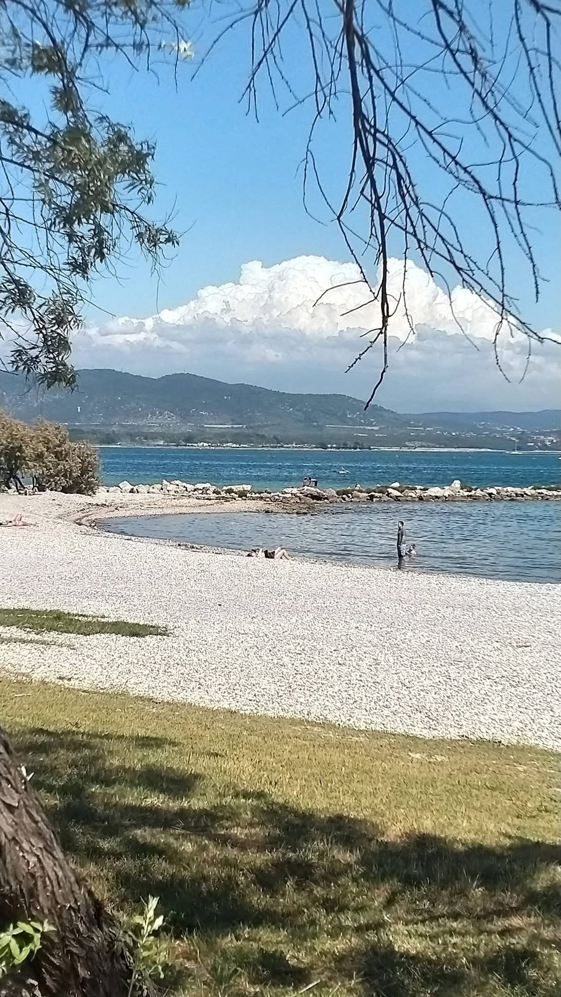Ein Kiesstrand mit freiem Blick auf das Meer und ferne Berge.