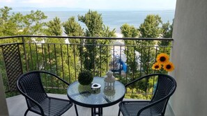 Un balcón con dos sillas, una mesa y un florero de girasoles.