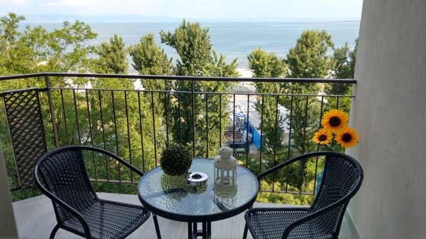 A balcony with two chairs, a table, and a vase of sunflowers.