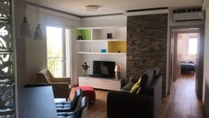 A modern living room with a TV, sofa, and dining area. - Bellavista (Marina Julia)