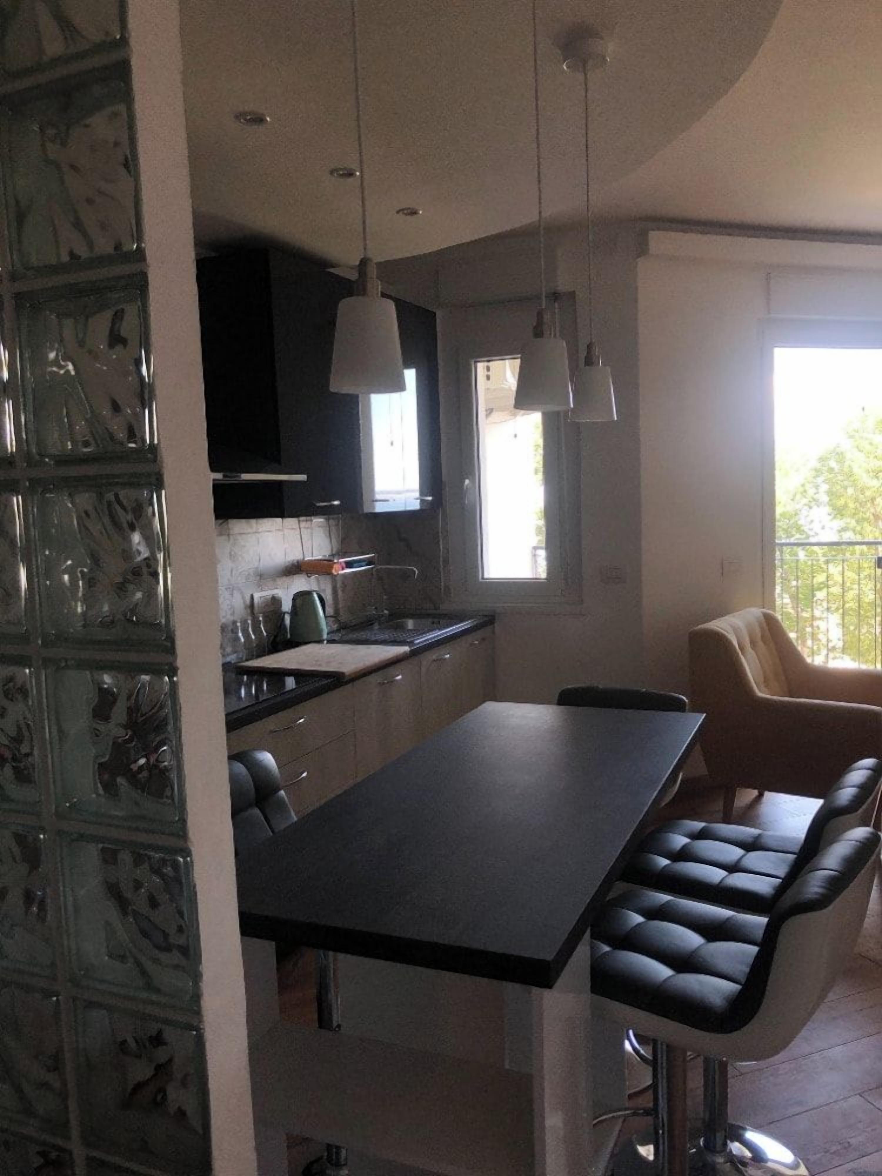 A modern kitchen with a central island, pendant lights, and a dining area with a bench.