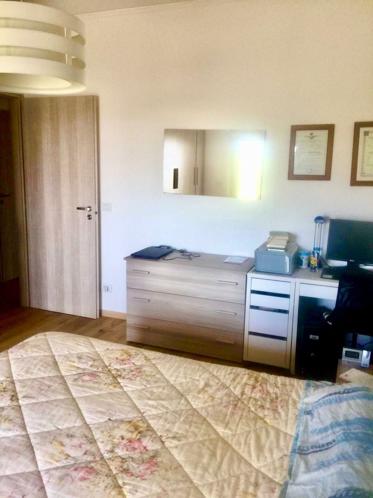 A bedroom with a bed, a dresser, a mirror, and a television.
