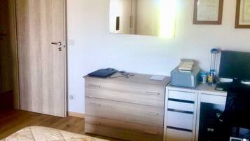 A bedroom with a bed, a dresser, a mirror, and a television.