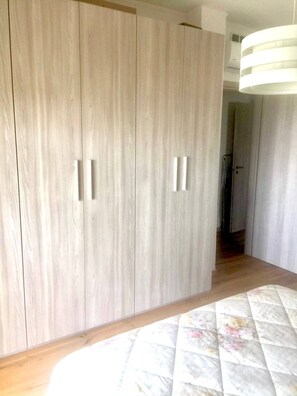 Una habitación con un armario grande, una cama con colcha estampada y un pasillo que conduce a otra habitación.