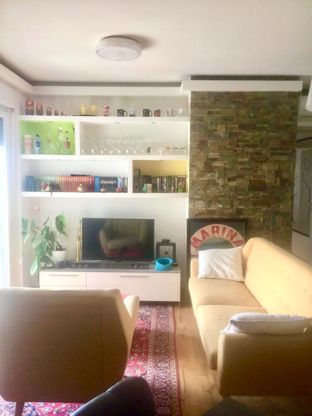 A living room with a sofa, television, and a bookshelf.