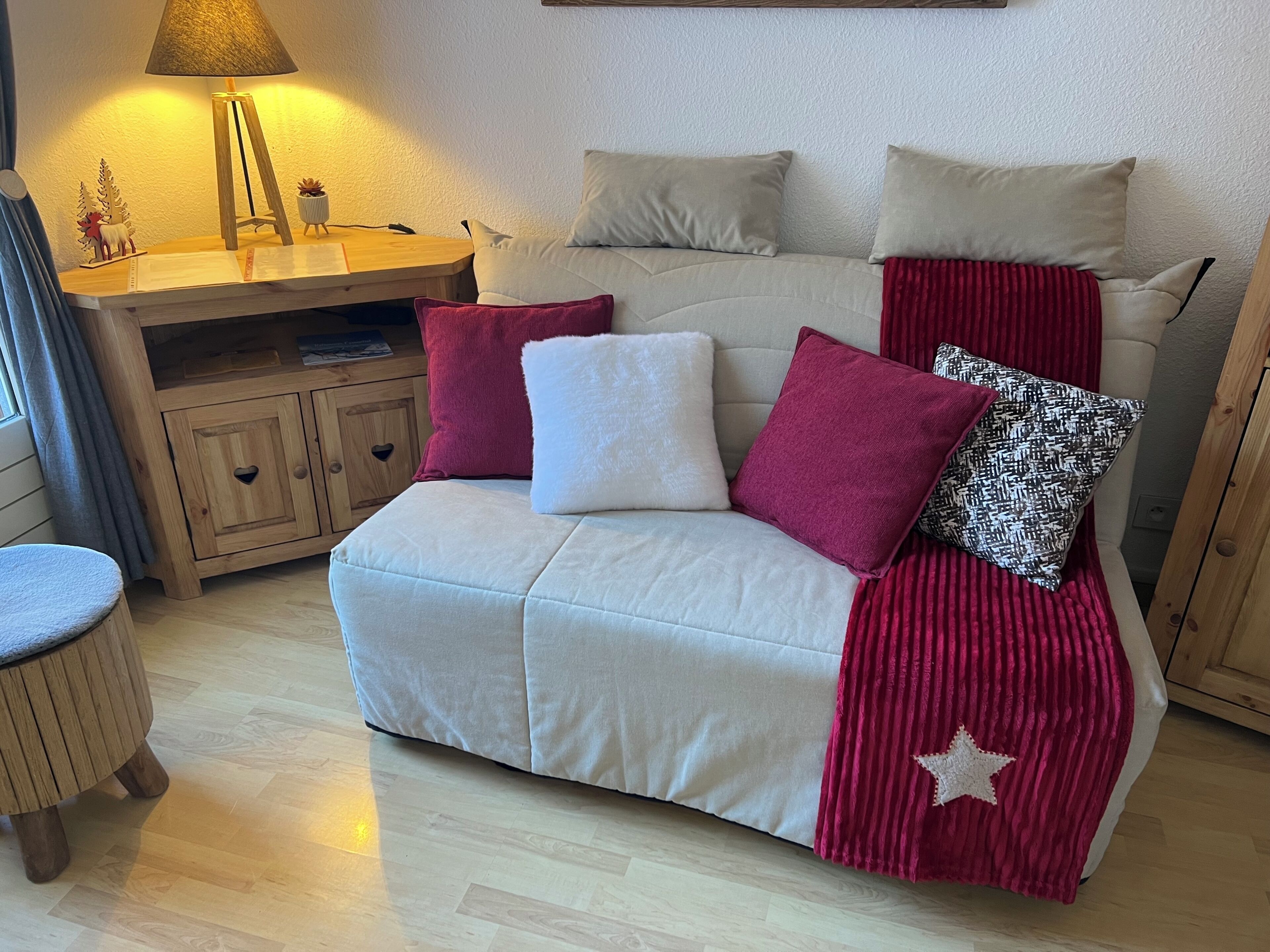 A cozy room with a sofa, pillows, a lamp, and a small table with decorative items.